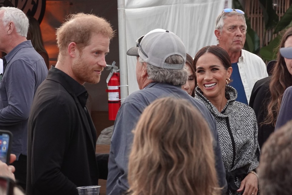 Harry chats with a punter while Meghan smiles widely at Friday's shindig