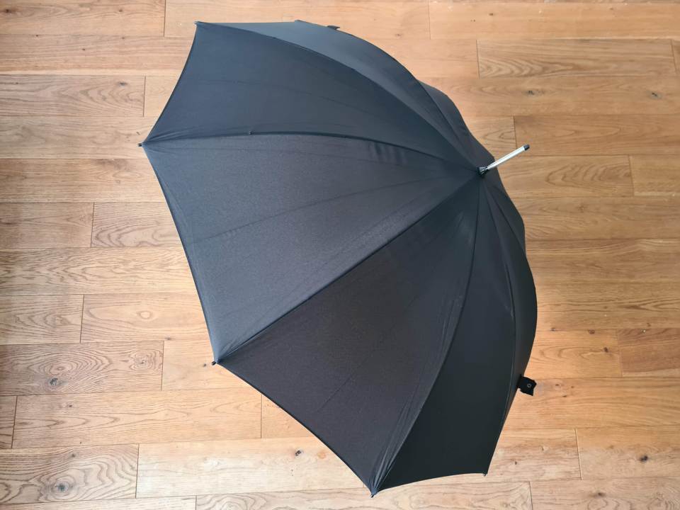 Black umbrella open on wooden floor.