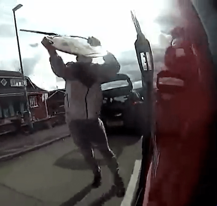 One of the thugs batters the lorry with a lollypop man sign