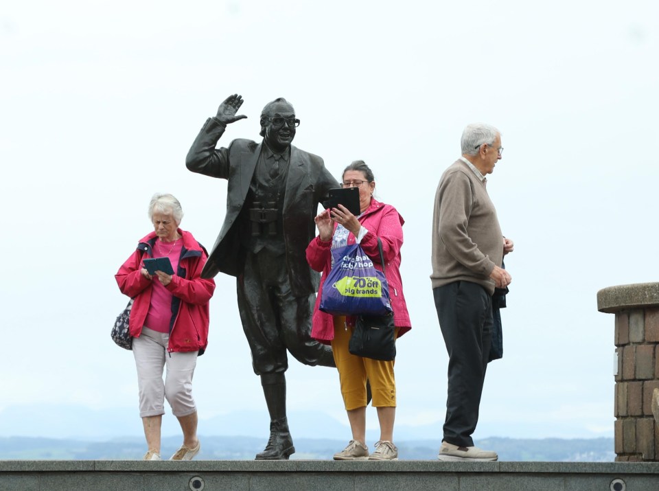 Locals pose with a statue of legendary figure Eric Morecambe