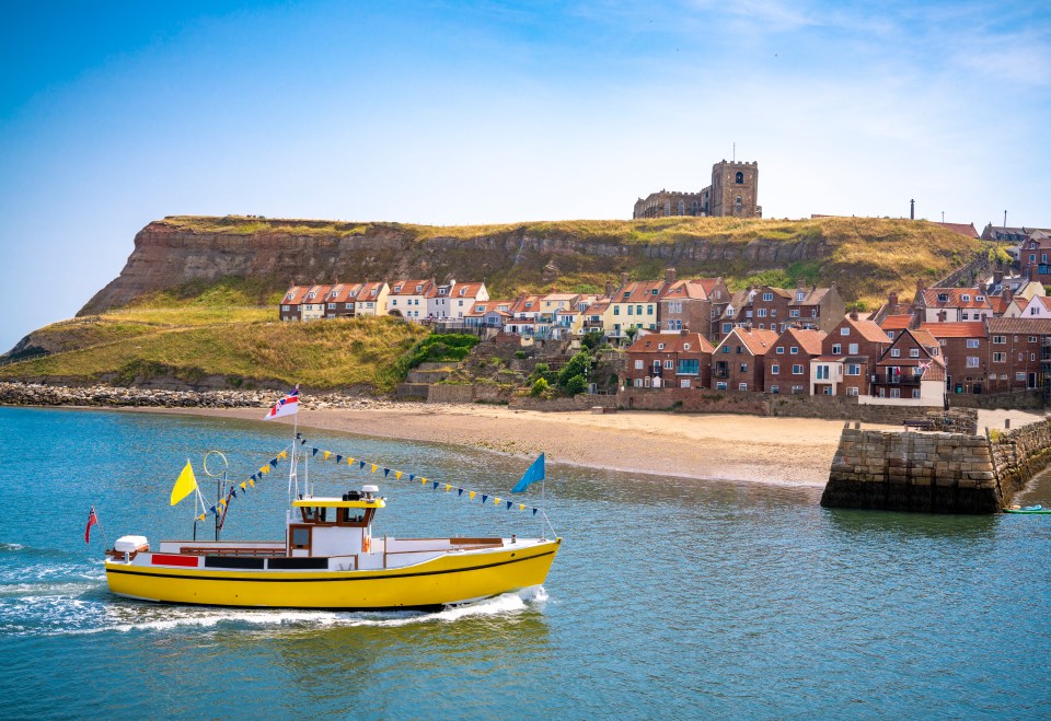 a yellow boat is in the water near a small town