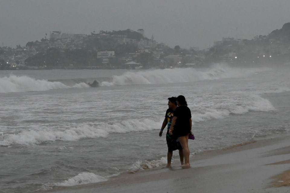 Brave people stand on the beach after Hurricane Otis’ arrival alert in Acapulco last night