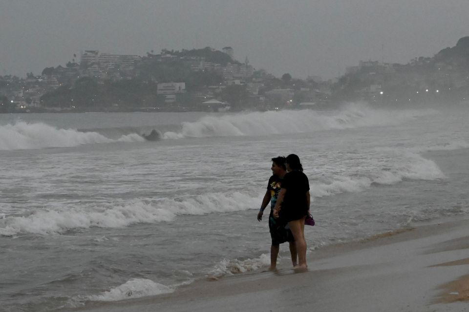 Brave people stand on the beach after Hurricane Otis' arrival alert in Acapulco last night