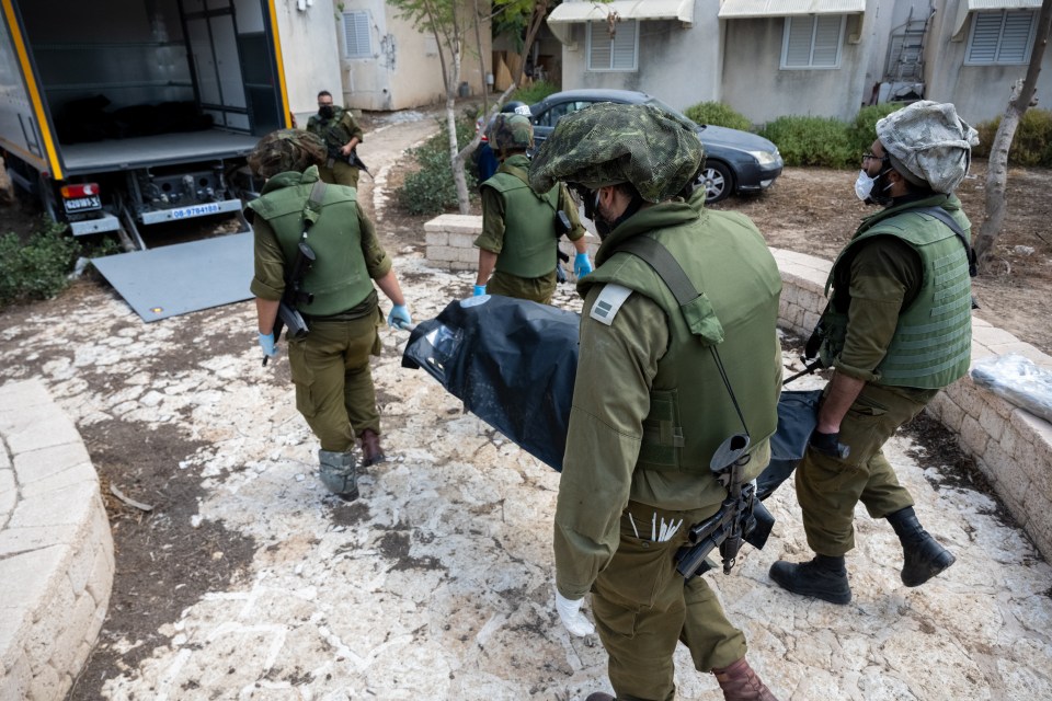 Israeli soldiers remove the bodies of civilians who were killed days earlier in an attack by Hamas terrorists in Kfar Aza