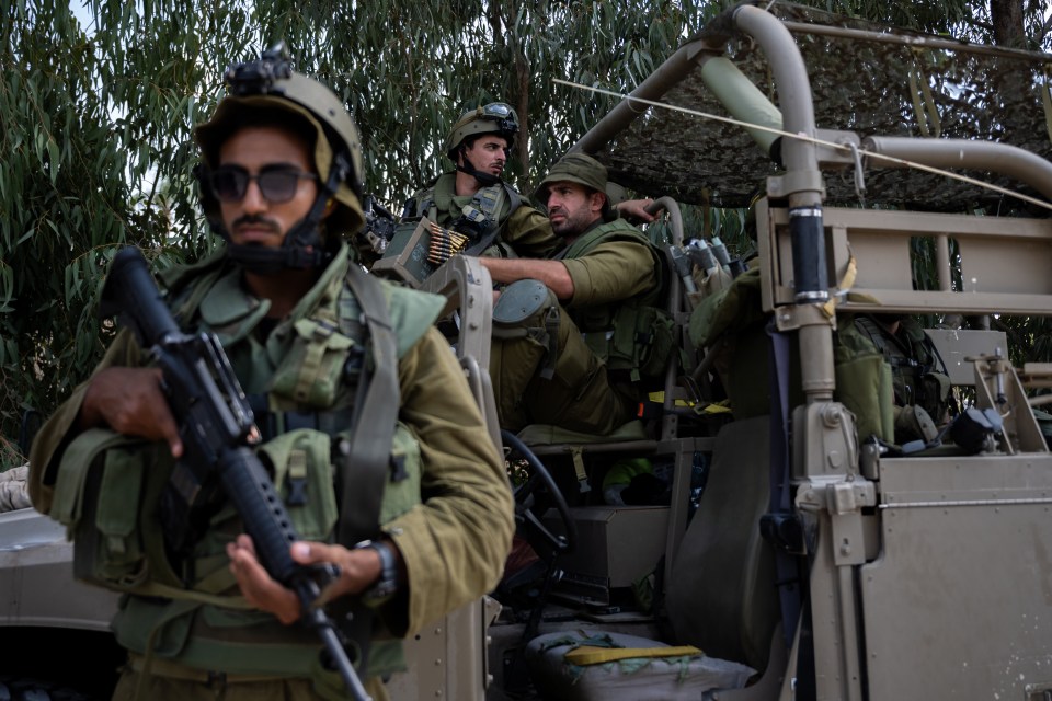 Israeli soldiers guard an area around Kfar Aza following the assault