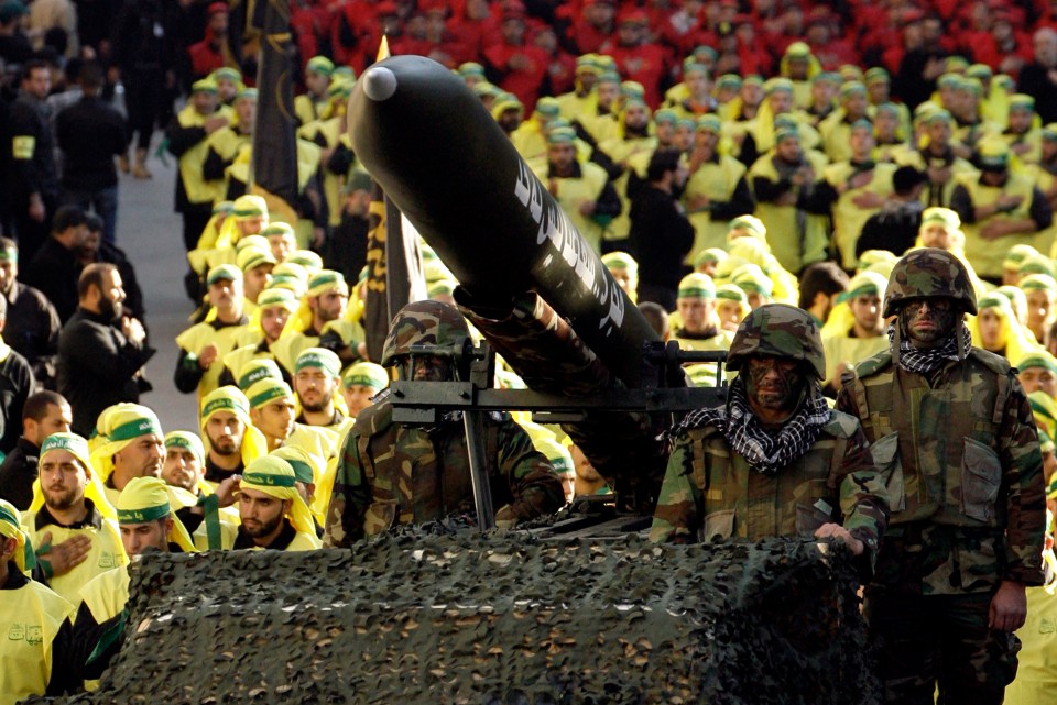 Hezbollah militants ride on a vehicle carrying a Fajr 5 missile