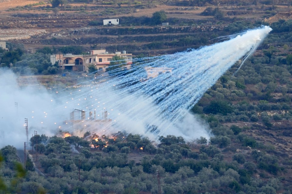 A shell explodes over a house in al-Bustan, a Lebanese border village with Israel