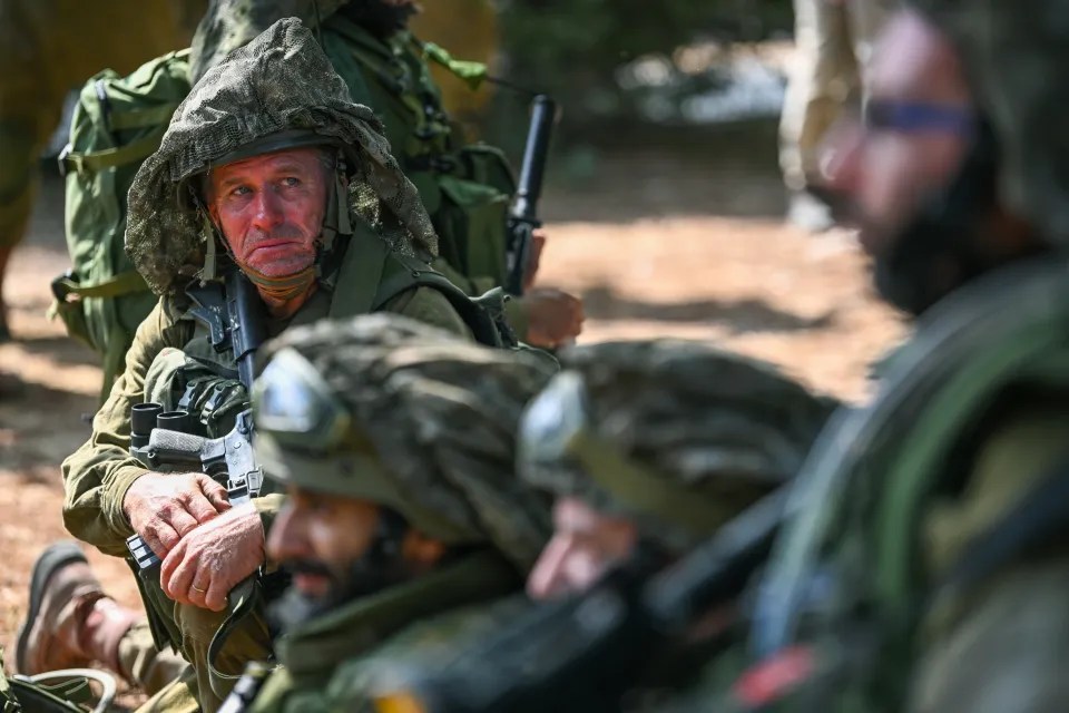 An IDF soldier sits with fellow troops at kibbutz Kfar Aza where dozens of civilians were killed days earlier