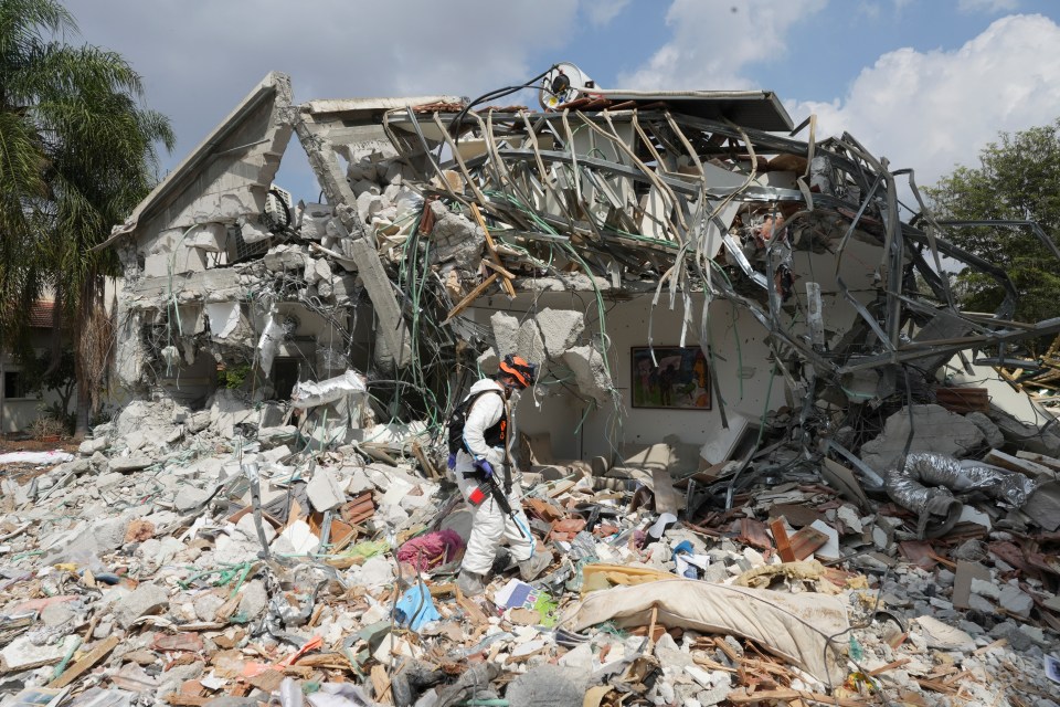 An Israeli soldier walks past a house destroyed by Hamas militants in Be'eri