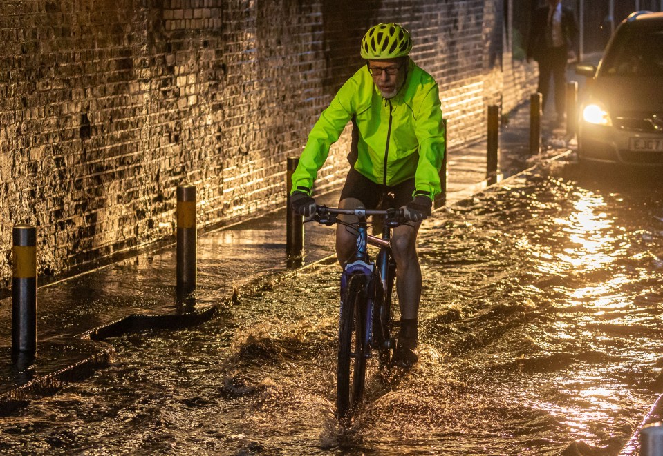 A cyclist caught in flooding in Wimbledon, south-west London