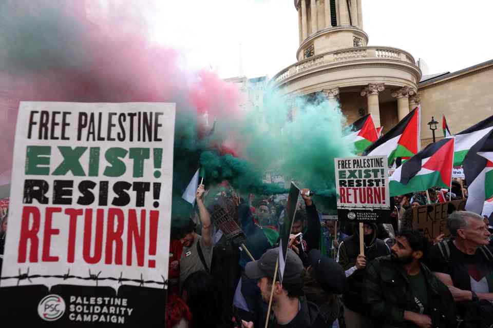 A protester lets off a smoke canister as people gather in London