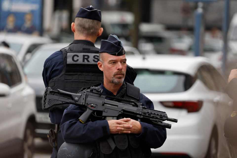 A police officer with an assault rifle as he stands guard near the Gambetta high school, where a teacher was murdered