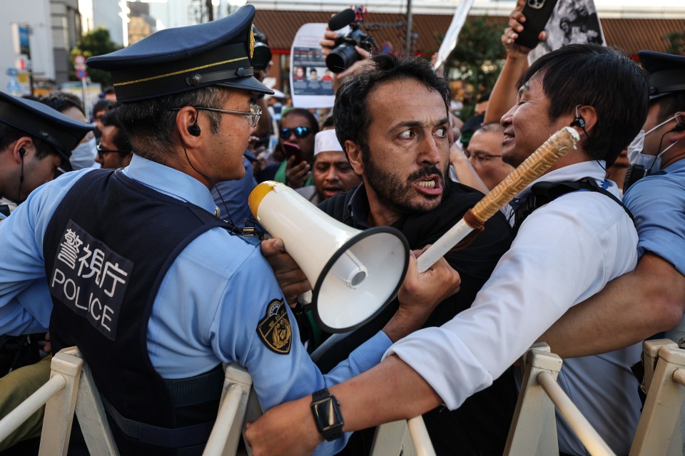 Police officers push back a man during a protest near the Embassy of Israel in Japan