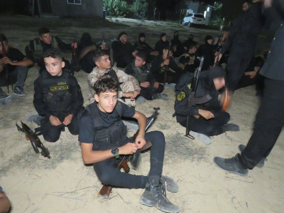 Images show boys, many holding a rifle, being schooled at a training camp