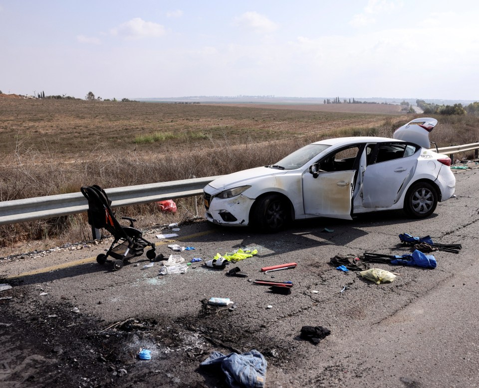 A child's buggy lies next to a car on the outskirts of the village of Kfar Aza