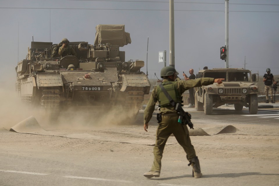 A soldier gives directions to a tank unit near the border with Gaza