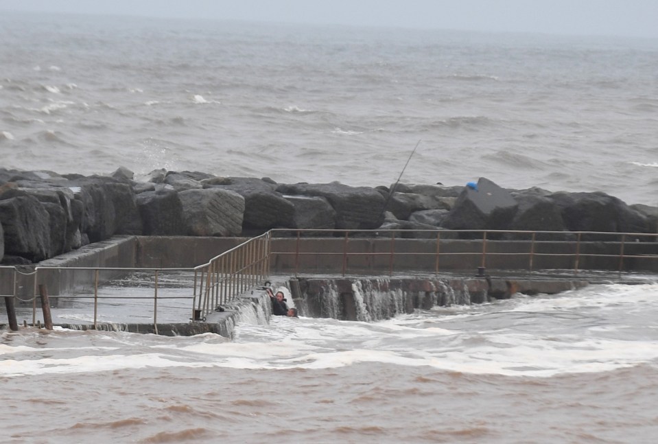 A couple cling on after being swept into the sea by a huge wave — as Storm Ciaran hurtles towards Britain.