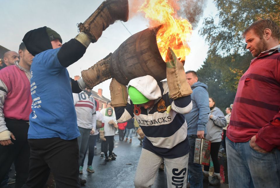 Children from the village of Ottery St Mary carry traditional burning tar barrels through the streets