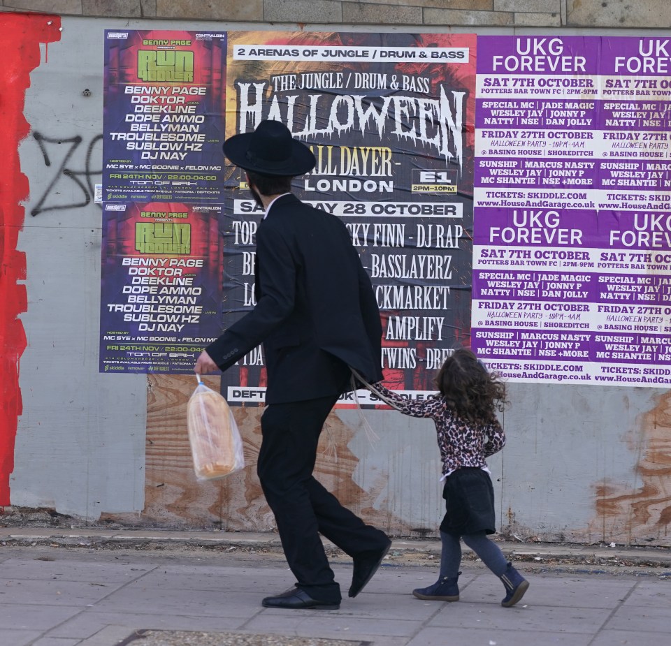 A Jewish man and young girl hurry along the street in Golders Green, North London