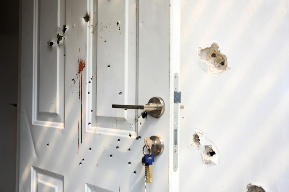 Gunshots and blood stains are seen on a door and walls of a house