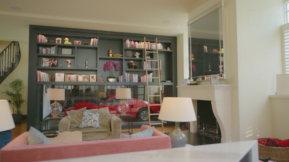 The room features a huge glass partition with a vintage red Ferrari behind