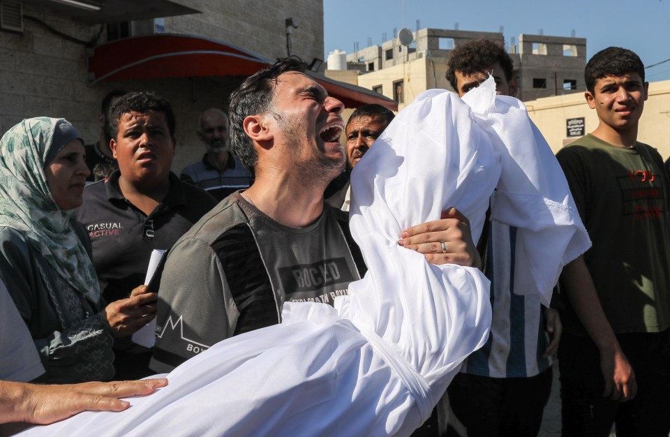 A man weeps as he carries a body from the morgue in Gaza