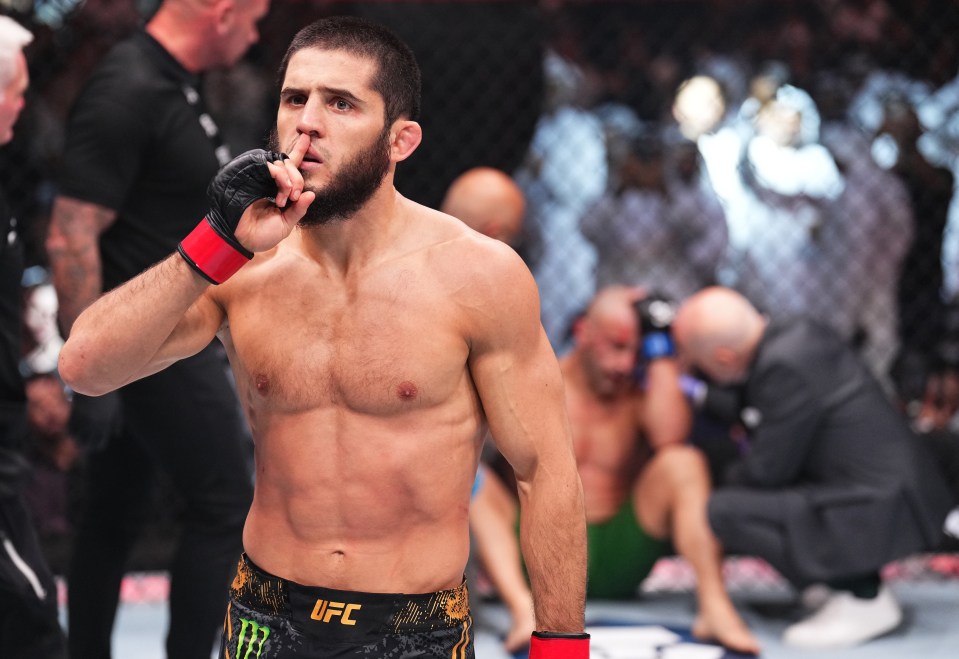 Islam Makhachev celebrates as Alexander Volkanovski is tended to by the doctor