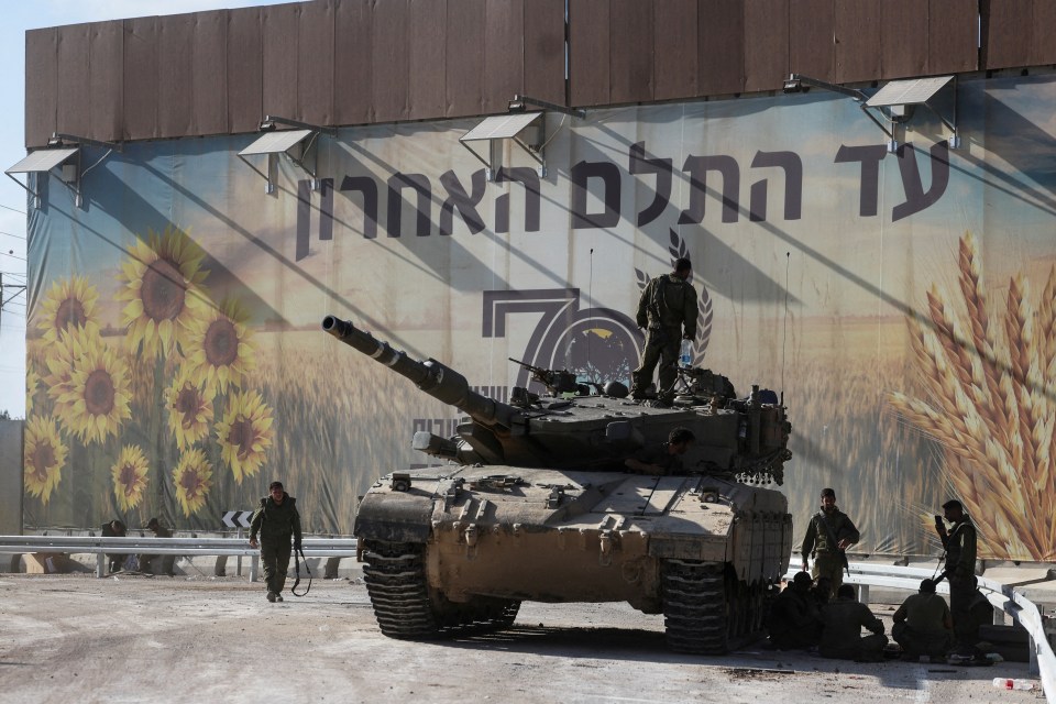 Israeli soldiers gather on and around a tank near the border with Gaza