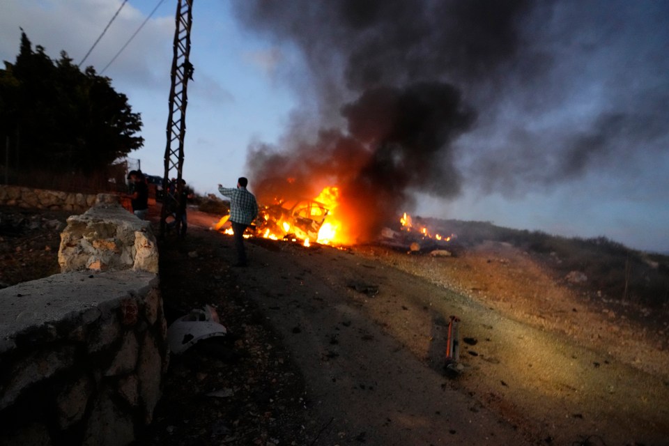 A car is scene ferociously burning in the aftermath of the strike that hit the journalists