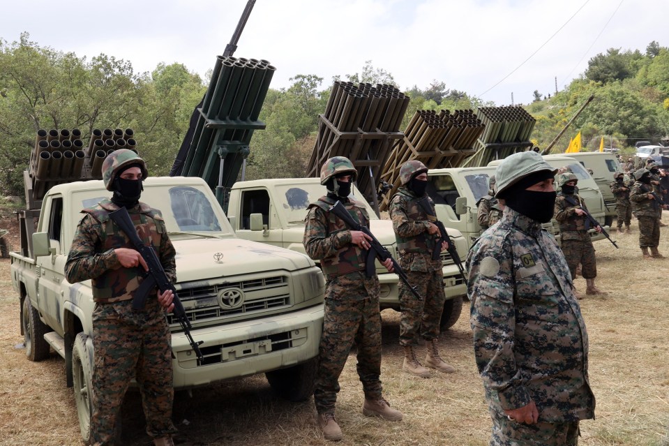 Lebanese Hezbollah fighters stand near multiple rocket launchers