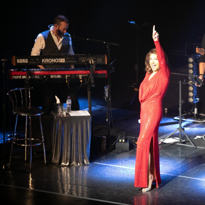 Jane McDonald turned heads on stage in a figure-hugging red sequin gown with a daring thigh-high split