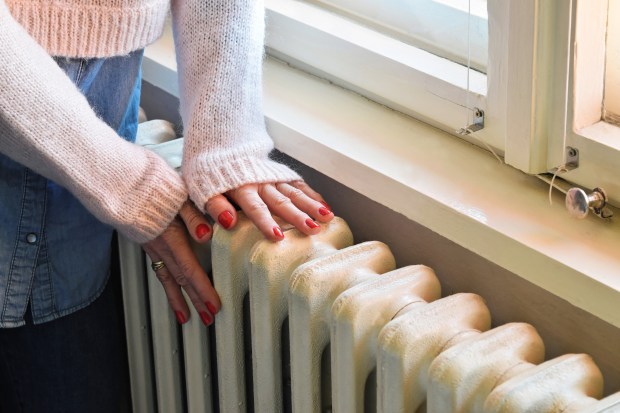 a woman in a pink sweater is touching a radiator