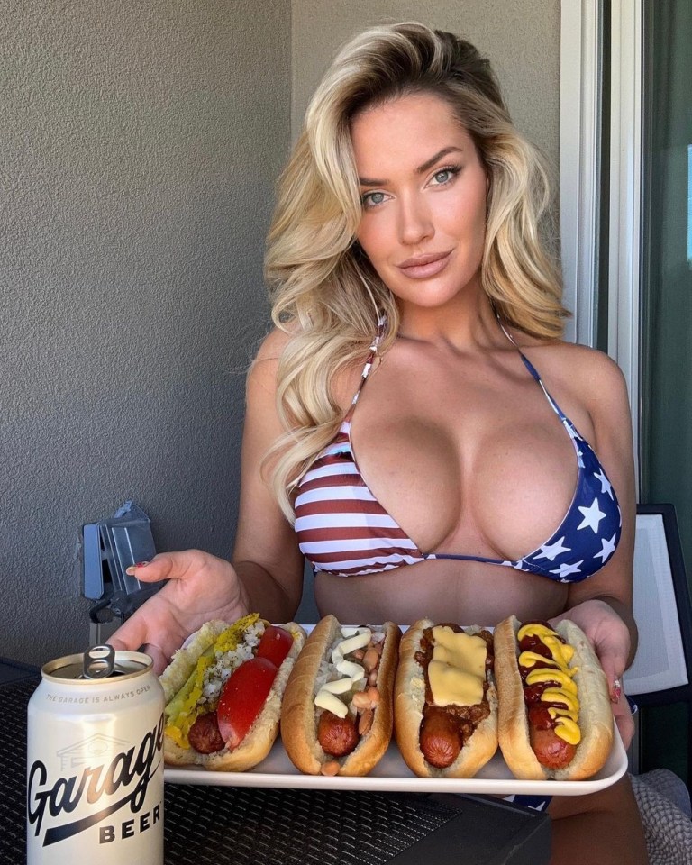 a woman in a bikini is holding a tray of hot dogs and a can of garage beer