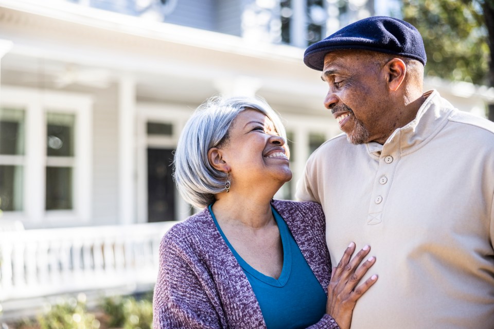 a man and woman are standing in front of a house and smiling