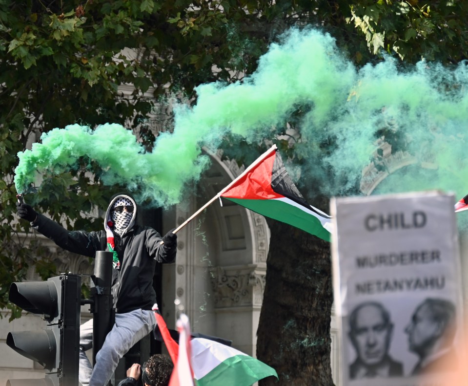 A pro Palestine support holds a flare during the Palestinian rally in Whitehall