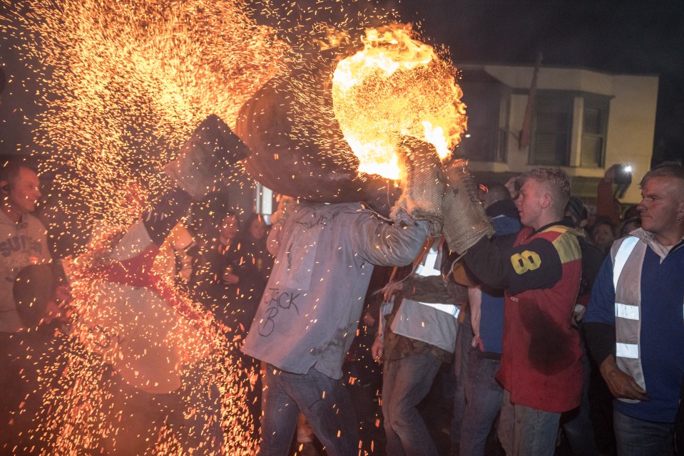 A participant runs with a burning barrel soaked in tar at a previous Ottery St Mary tar barrel festival