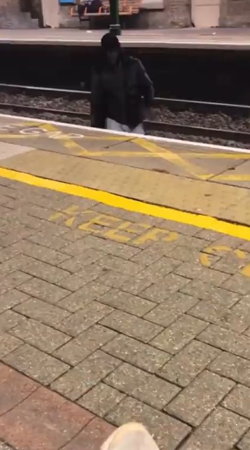 A woman has snapped the moment she says a man jumped across the tracks at a station to talk to her