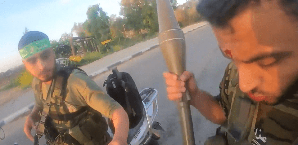 The two Hamas terrorists can be seen stalking through an Israeli community with assault rifles and grenades