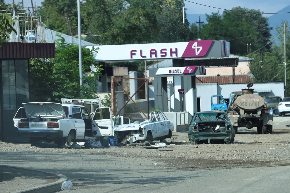 Broken and smashed cars lie close to a petrol station in the hastily abandoned city