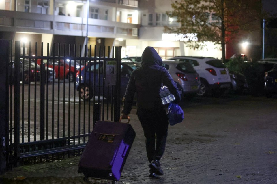 A resident leaves the block of flats with bottles water and a suitcase on Tuesday night