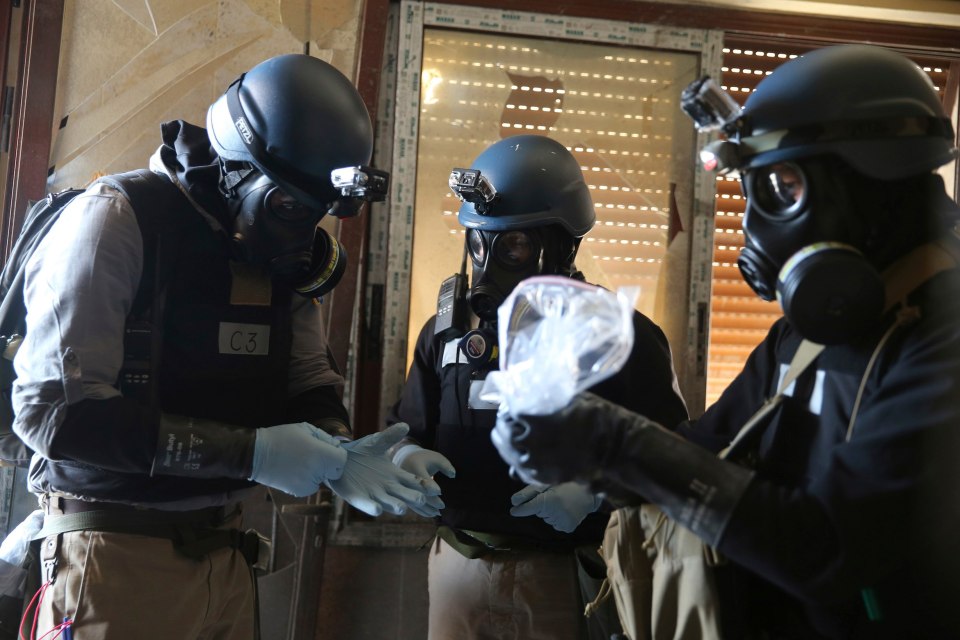 A U.N. chemical weapons expert, wearing a gas mask, holds a plastic bag containing samples from one of the sites in 2013