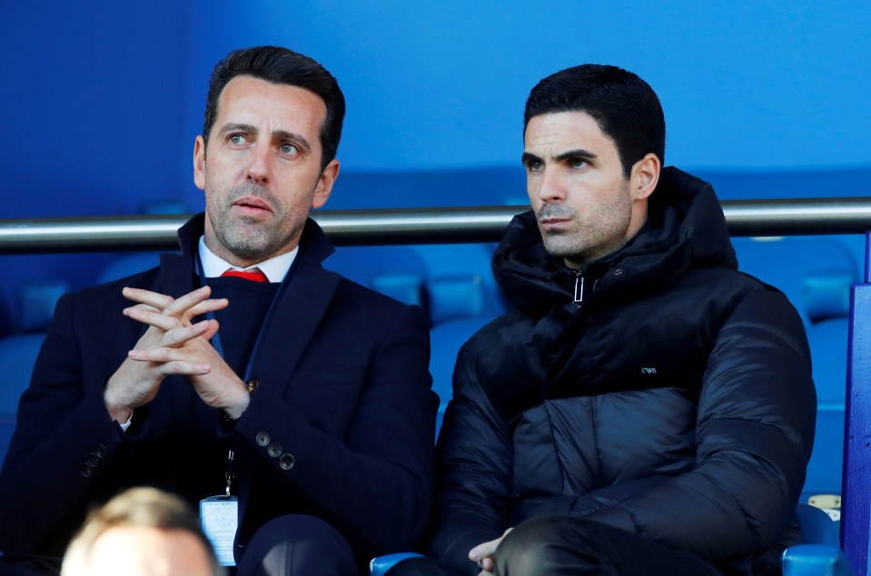 two men sitting in a stadium with one wearing a jacket that says nm