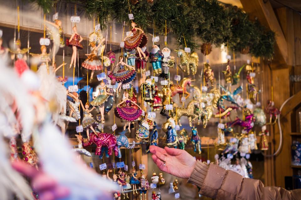 The wooden market stalls sell a selection of homemade gifts, including woolen mittens, sweaters, and wooden ornaments