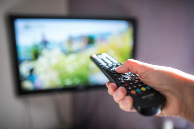 a person is holding a remote control in front of a tv