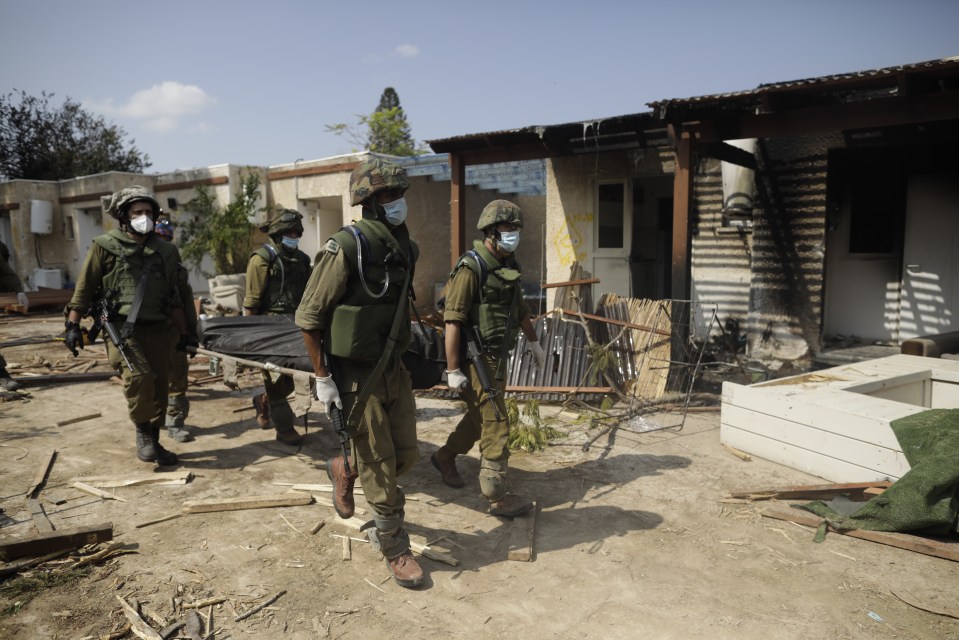 Israeli soldiers remove bodies on a kibbutz near the border with Gaza after the Hamas attacks. Witnesses now say some victims were beheaded