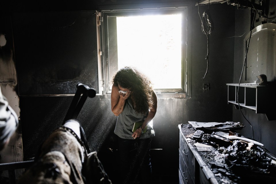 Kibbutz Nir Oz resident Hadas Kalderon, who's children have been taken hostage, and mother and niece killed in tears while looking through the burnt out home of her late mother