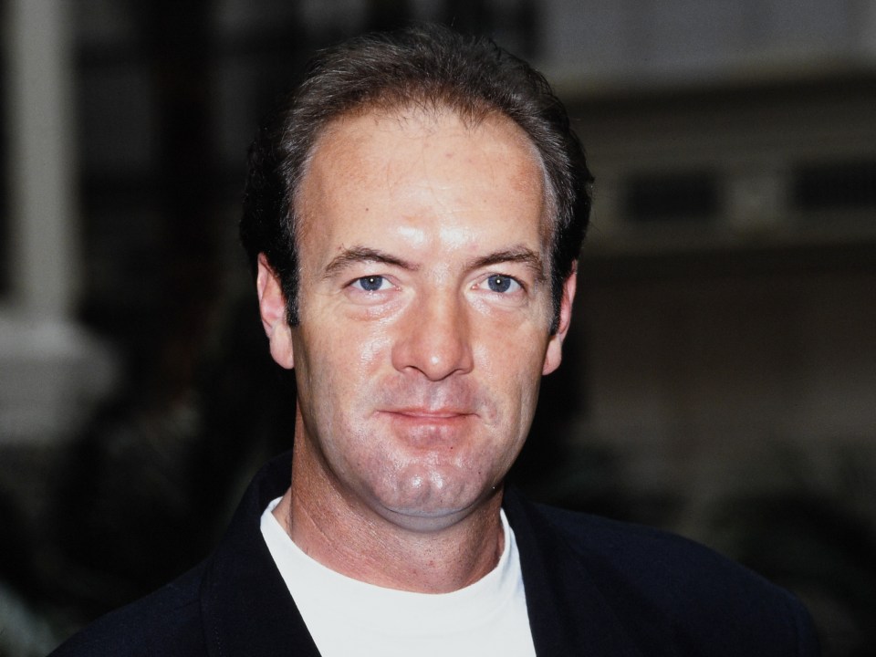 a man with a white shirt and a black jacket looks at the camera