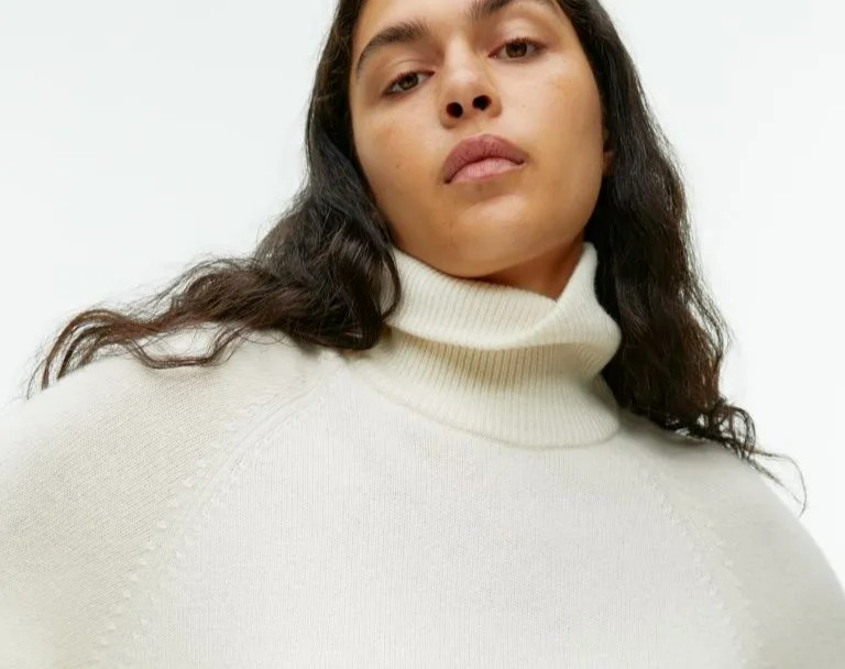 Woman wearing an off-white turtleneck sweater.