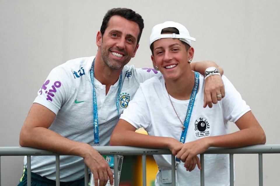 a man and a boy are posing for a picture and the boy has a lanyard around his neck that says fifa