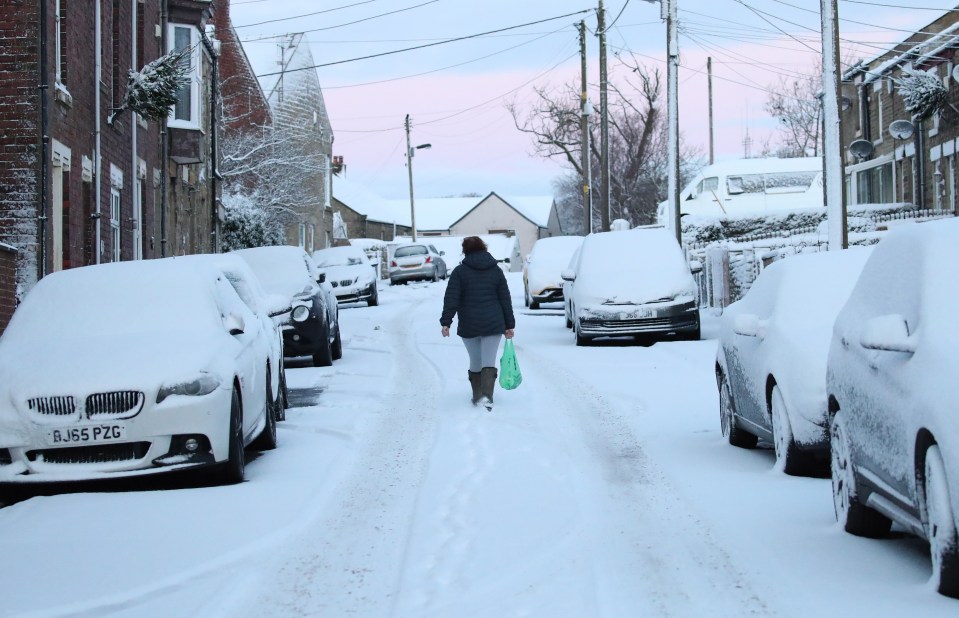 Cars remain parked at the side of the snowy streets of Gateshaed